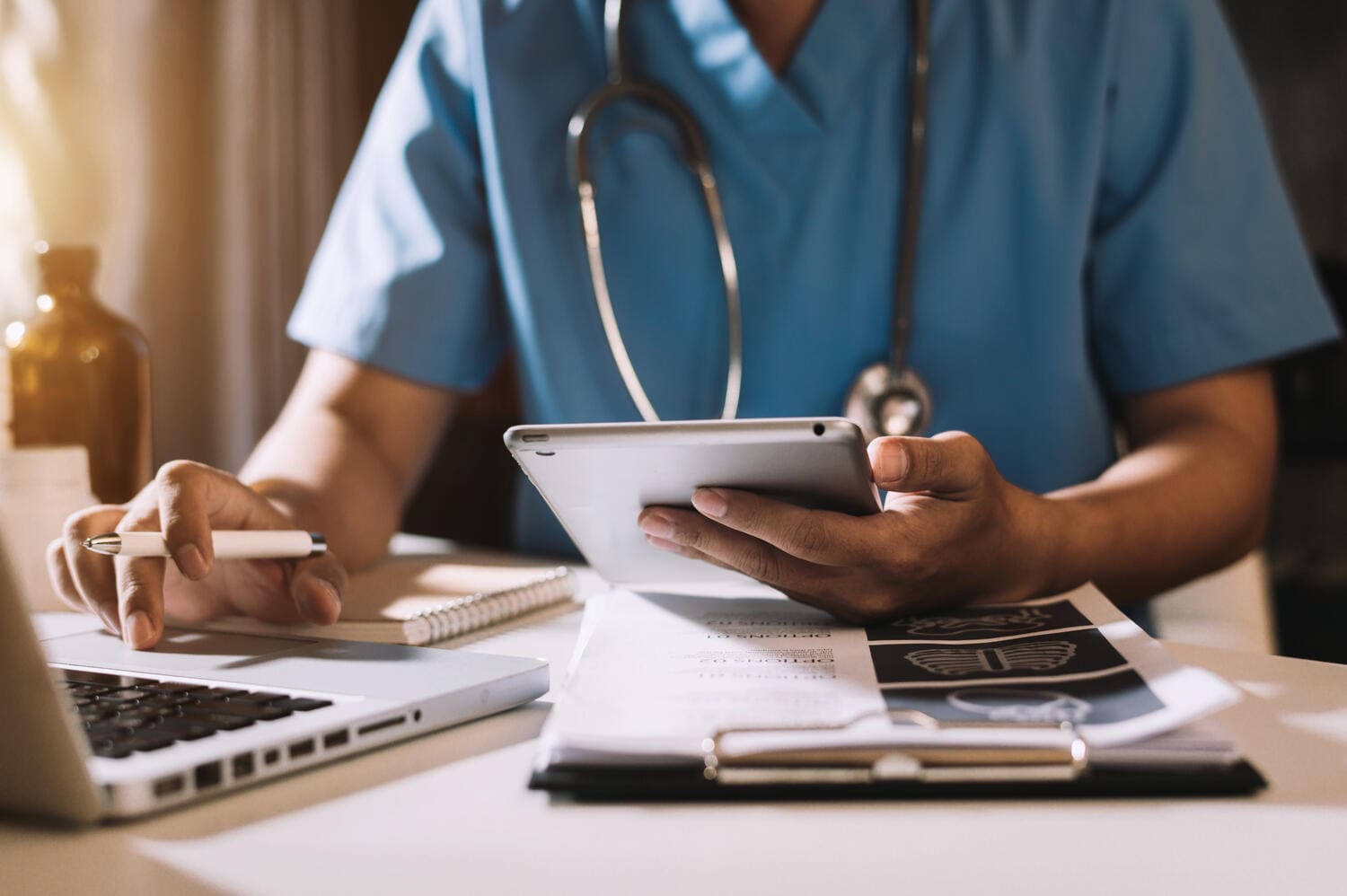 Doctor holding tablet and using laptop while analyzing data