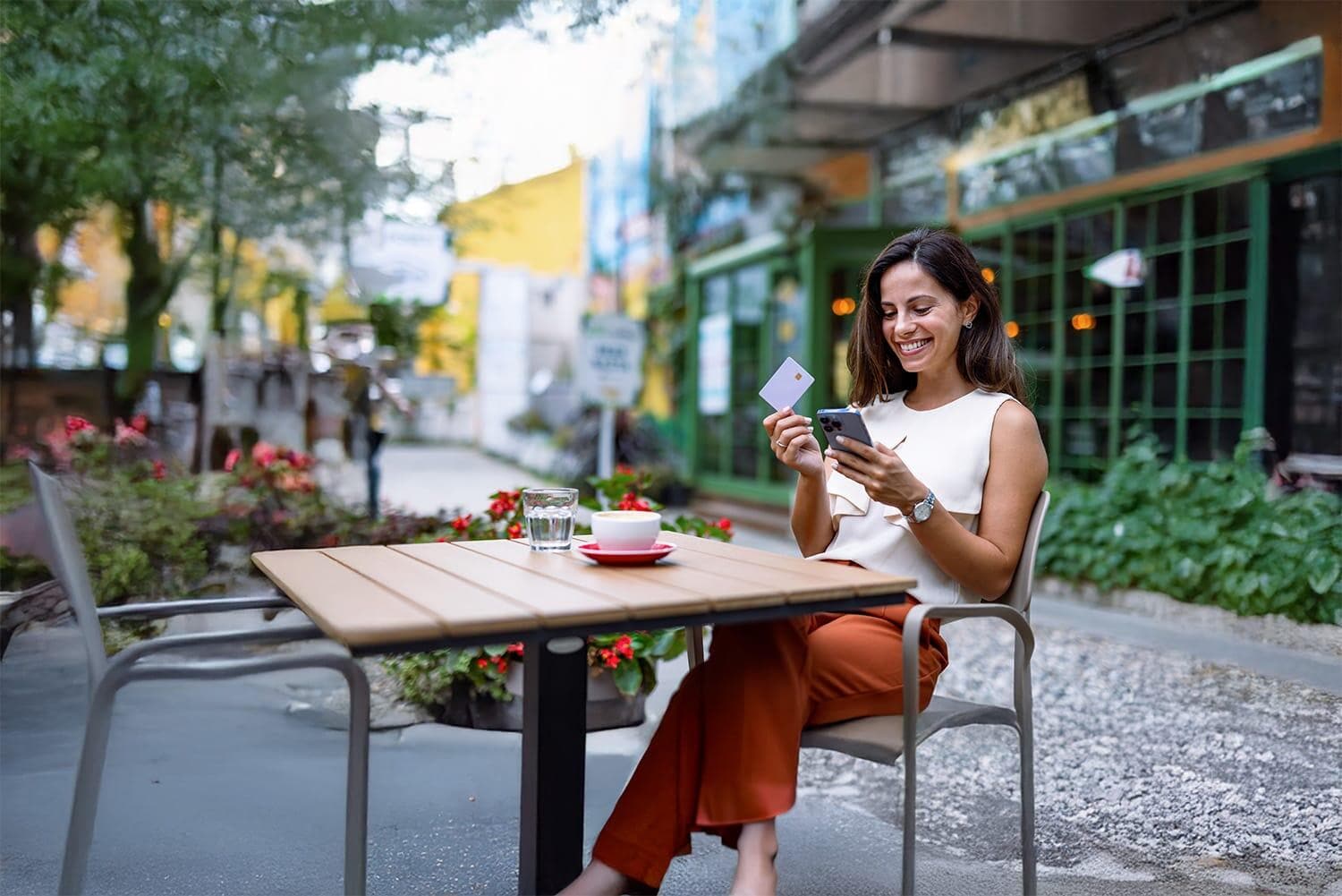 Woman at outdoor cafe on smartphone with credit card Woman at outdoor cafe on smartphone with credit card
